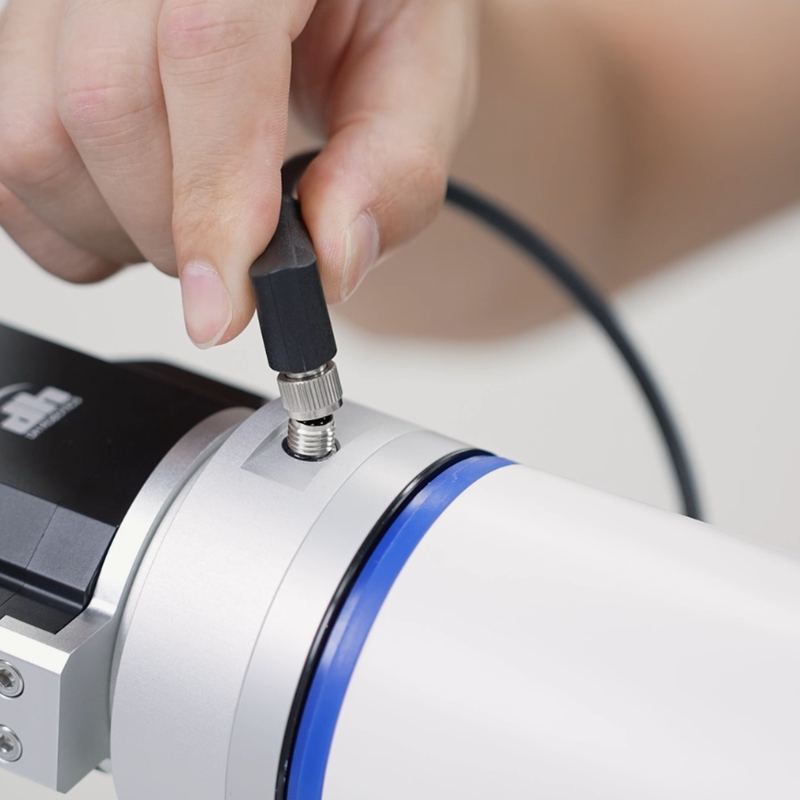 Close-up of a two-jaw gripper on a cobot flange, with a connector cable being plugged in.