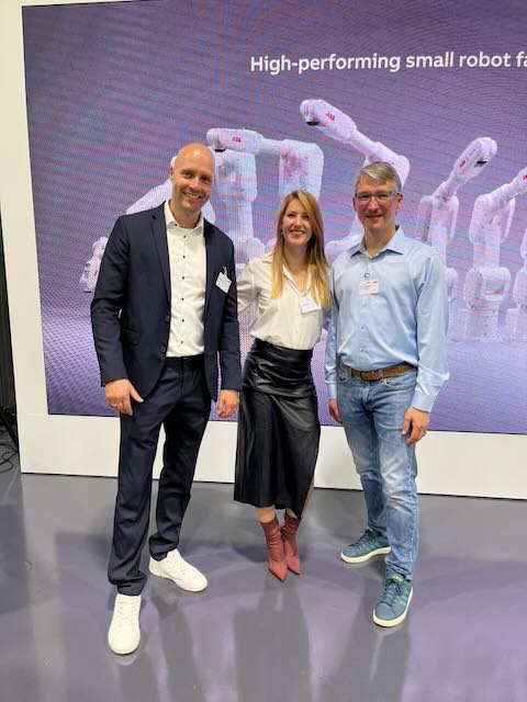 Drei Personen vor einer ABB-Anzeige mit Cobot-Armen auf dem ABB-Cobot-Partnermeeting 2025.