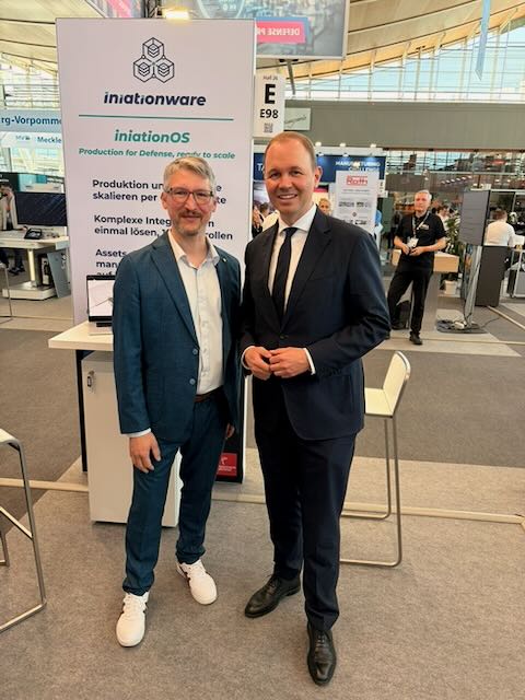Zwei Personen vor dem iniationWARE-Banner zu iniationOS auf der Hannover Messe 2026.