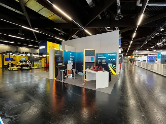 iniationWARE booth at SPS Nuremberg 2025 with dark wall panels, orange light strips and a counter with demo hardware.