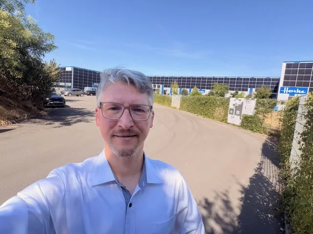 Klaus Landsdorf in front of a production hall with a photovoltaic façade at an industrial site.